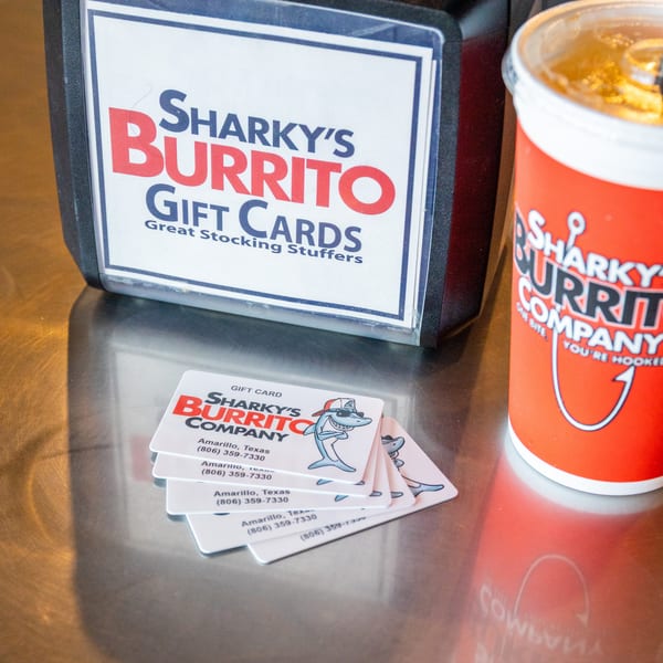 Sharky’s Burrito Company gift cards sit beside a branded cup on a restaurant table.